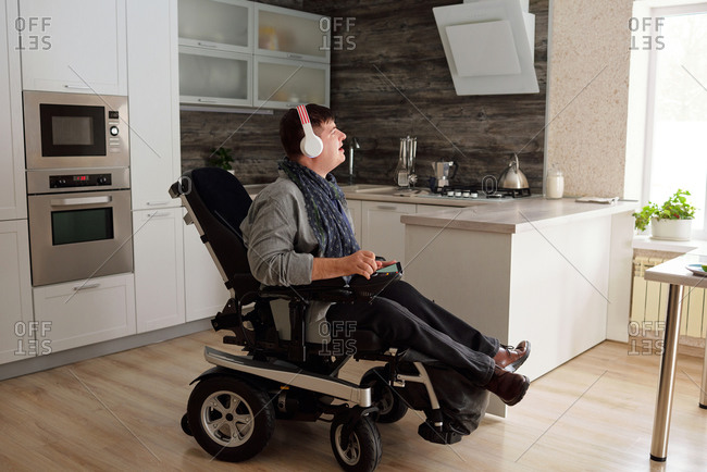 Physically impaired man listening to music with headphones at home