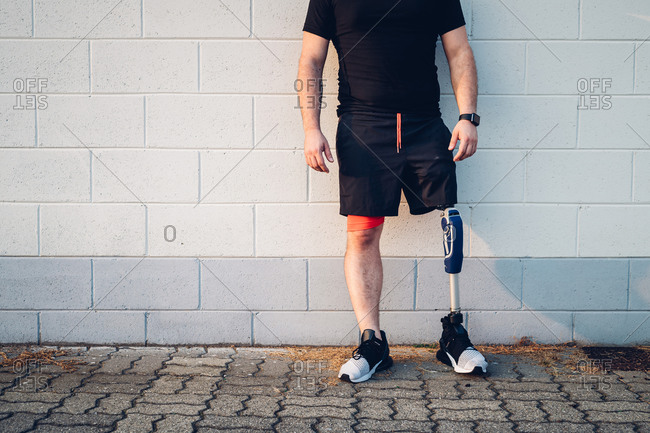 Man with prosthetic leg leaning on wall