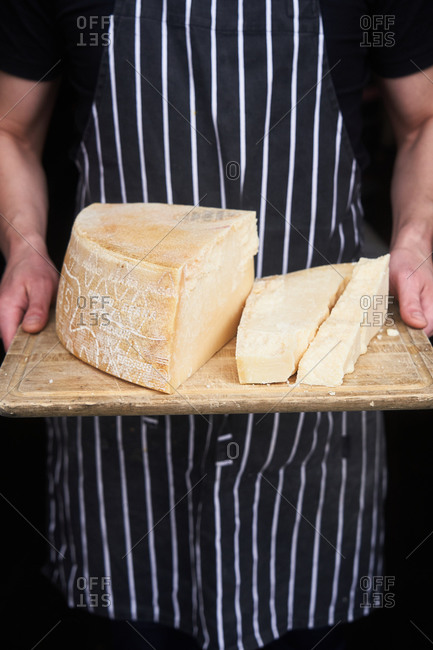 Closeup of a man slicing a Parmigiano Reggiano cheese wheel Stock