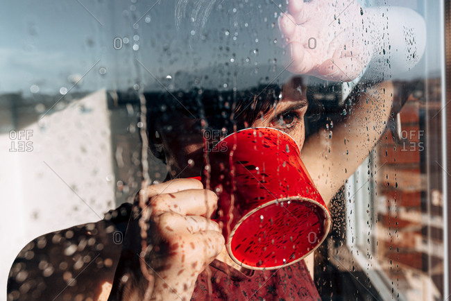 Thoughtful woman drinking coffee near window