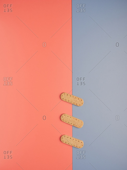 Top view of yummy crunchy cookies arranged in line like patches between gray and coral backgrounds