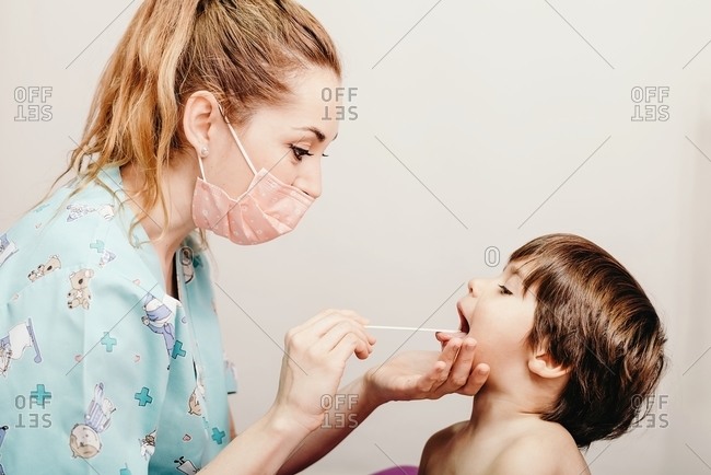 Pediatrician examining throat of little patient