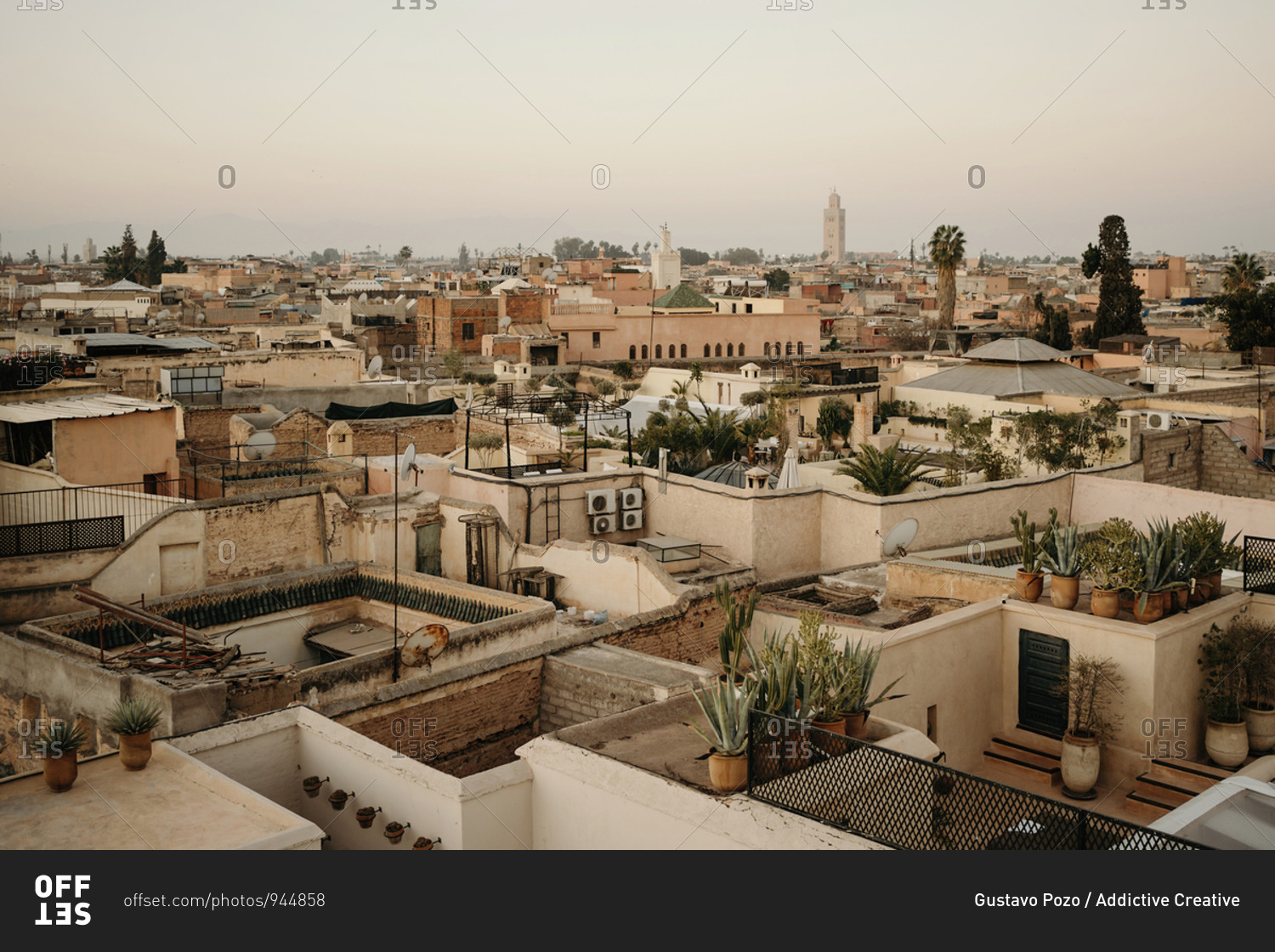 From above aerial view amazing cityscape of ancient Marrakesh city with stone houses and green potted plants placed on roofs under clear morning sky