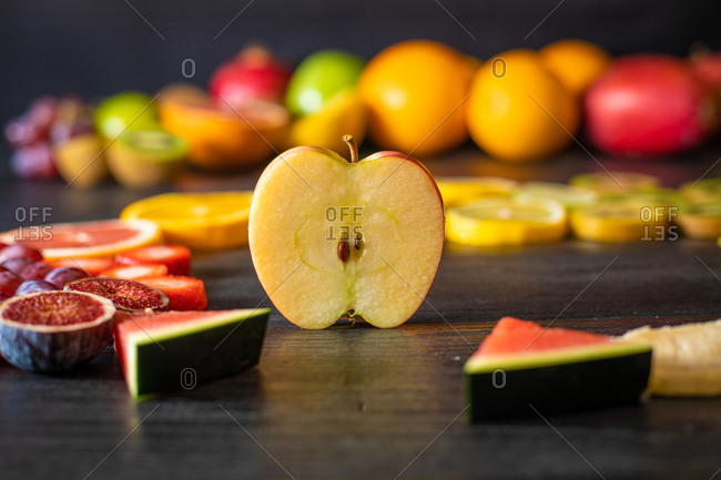 Various peeled and cut healthy fruits and vegetables arranged on a black lumber table