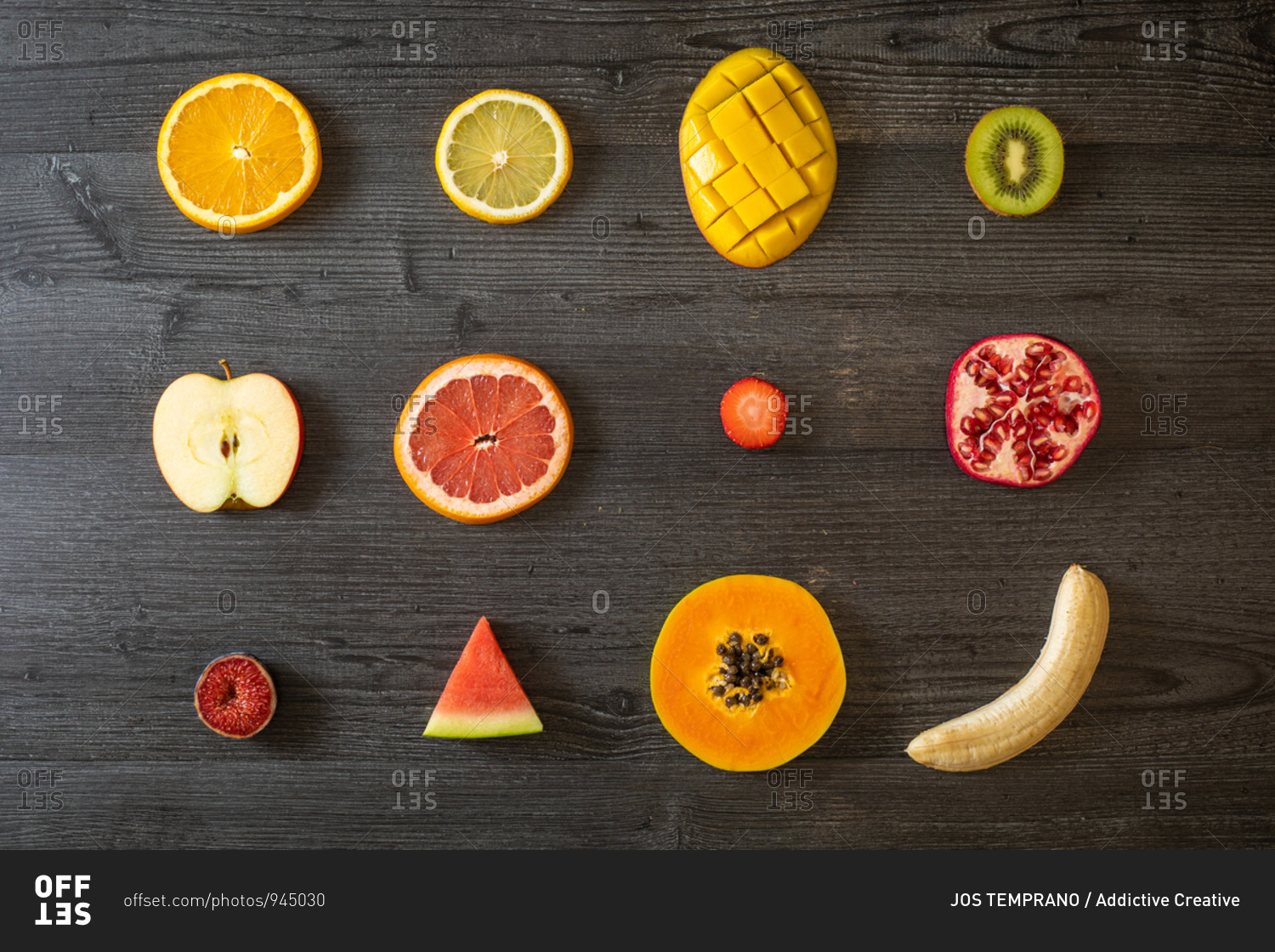 Top view of various peeled and cut healthy fruits and vegetables arranged on black lumber table