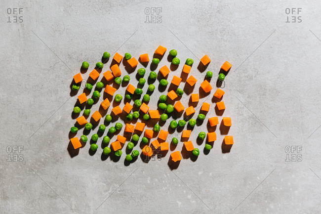 Frozen peas and diced carrots on gray background