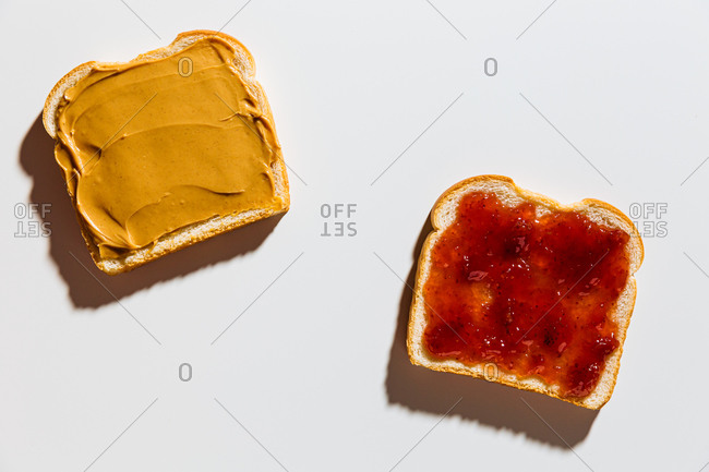 Peanut butter and jelly sandwich being prepared on white background