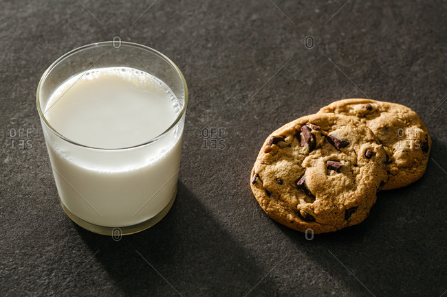A glass of milk and two chocolate chip cookies