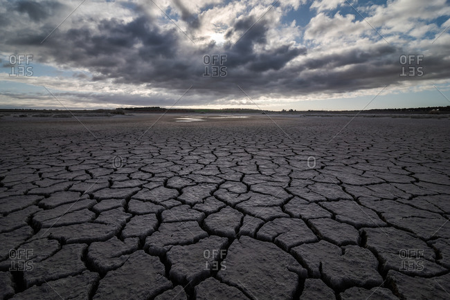From above of drought cracked lifeless ground under colorful cloudy sky