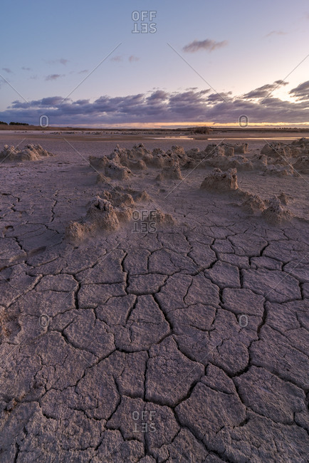 From above of drought cracked lifeless ground under colorful cloudy sky at sunset time