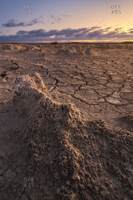 From above of drought cracked lifeless ground under colorful cloudy sky at sunset time