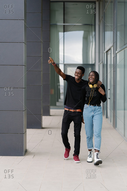 Happy black couple walking outside modern building