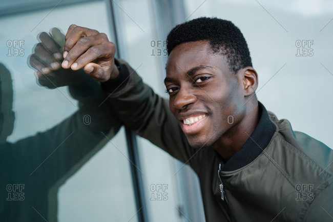 Friendly black man leaning on glass wall