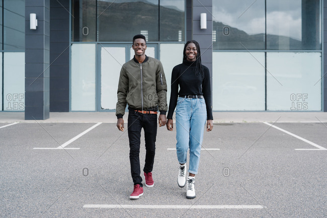 Happy black couple walking outside modern building