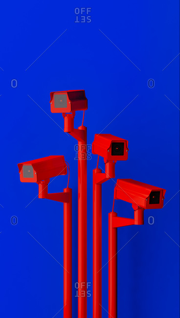 Red surveillance camera on blue background monitoring people on the street. Camera to search for quarantine offenders caused by Coronavirus