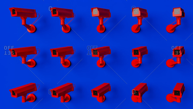 Red surveillance camera on blue background monitoring people on the street. Camera to search for quarantine offenders caused by Coronavirus