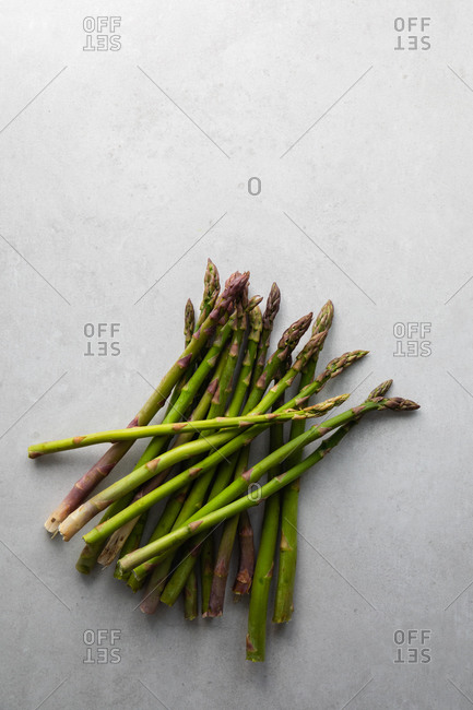 Top view of bunch of fresh green asparagus prepared for healthy vegetarian salad placed on marble table