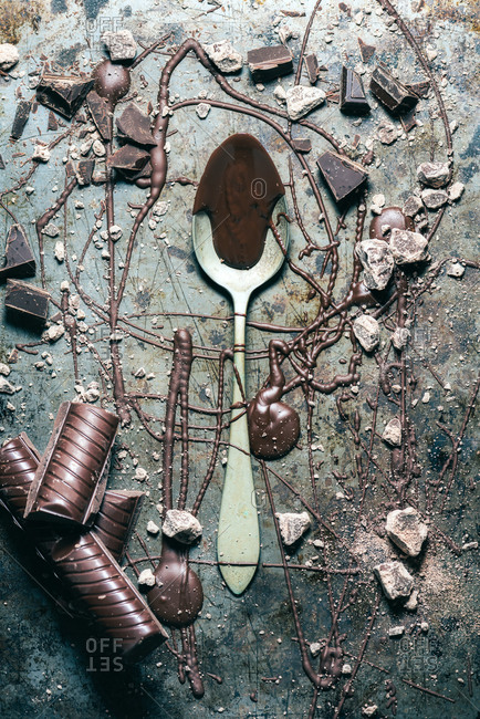 From above top view spoon with chocolate spilled over rustic metal surface background