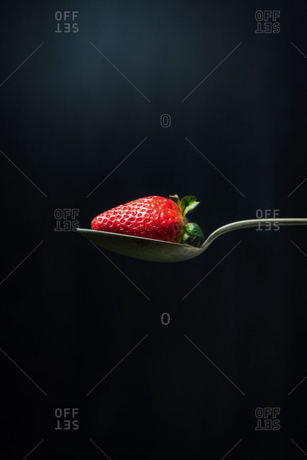Strawberry in a spoon on dark background