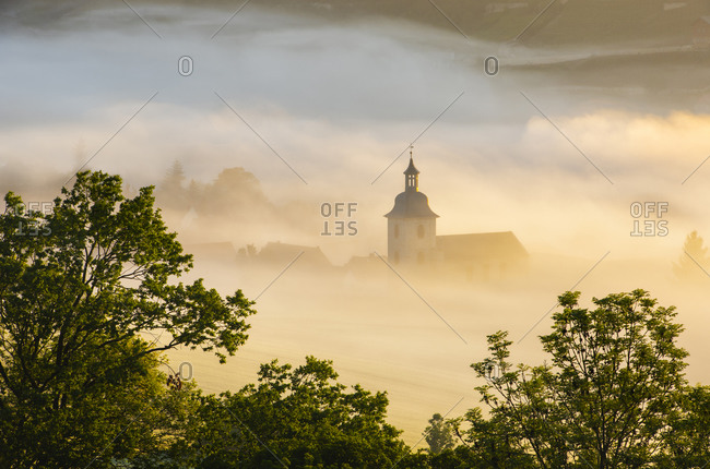 The village church of Nissmitz rises out of the morning fog, Freyburg (Unstrut), Saxony-Anhalt, Germany
