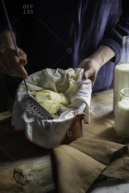 Hands collecting a homemade mascarpone cheese with a slotted spoon on a vintage atmosphere