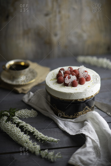 Uncooked creamy cheesecake decorated with fresh raspberries ready to get shared