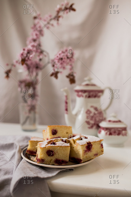 Cherry cake slices on a plate with tea and cherry blossoms