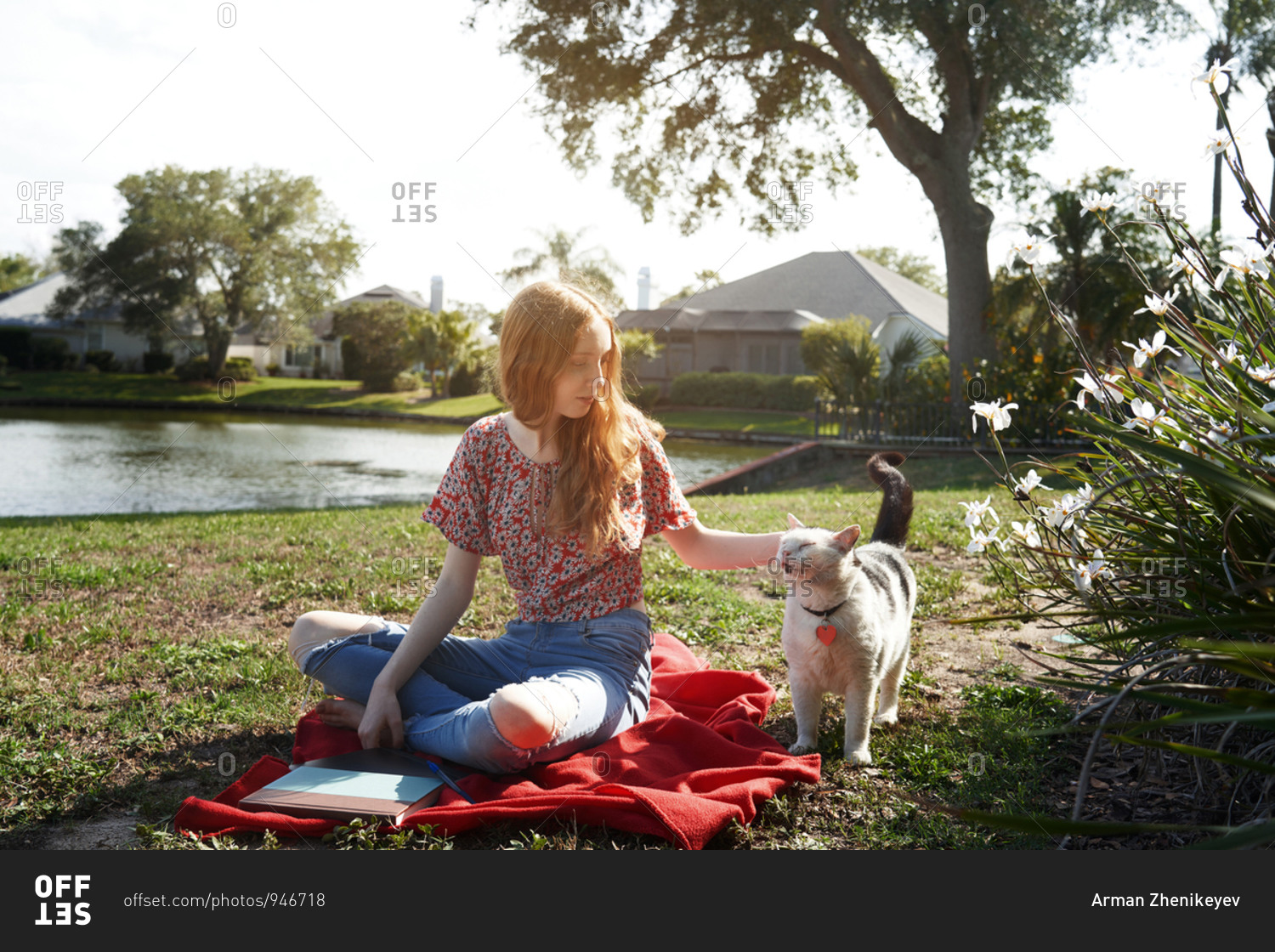 Smiling teenage girl relaxing next to the lake with her pet cat