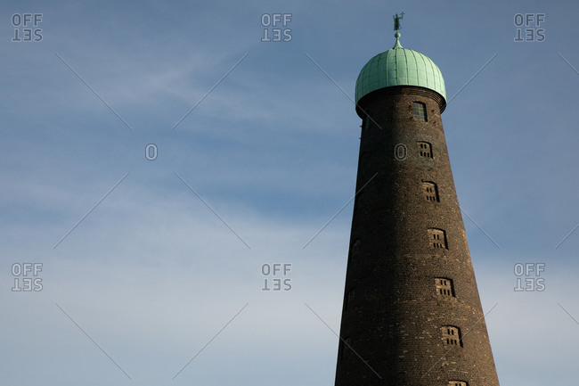 Brick conical tower against blue cloudy sky