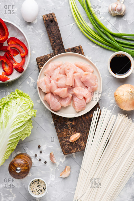 Fresh chicken meat, vegetables and spices for cooking asian noodle dish on gray background