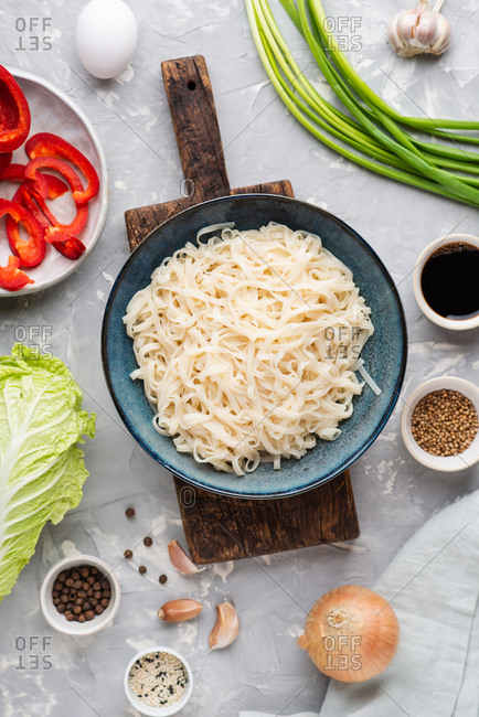 Asian udon noodles with ingredients for cooking on gray background