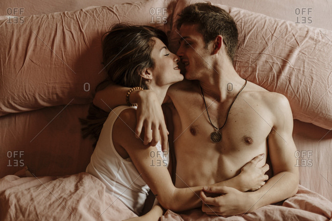 young couple kissing bed stock photos - OFFSET