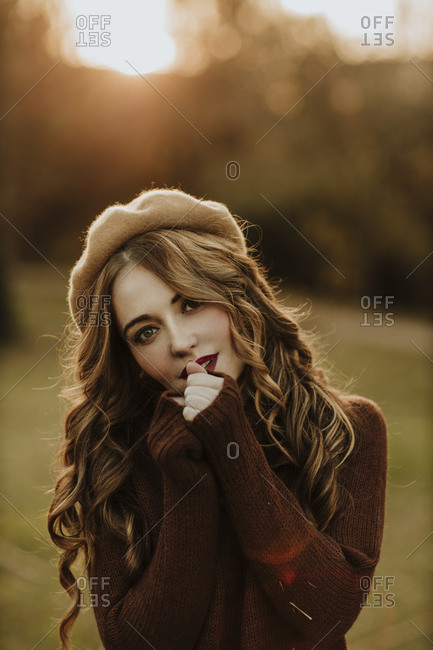 Portrait of fashionable woman standing on a meadow at backlight