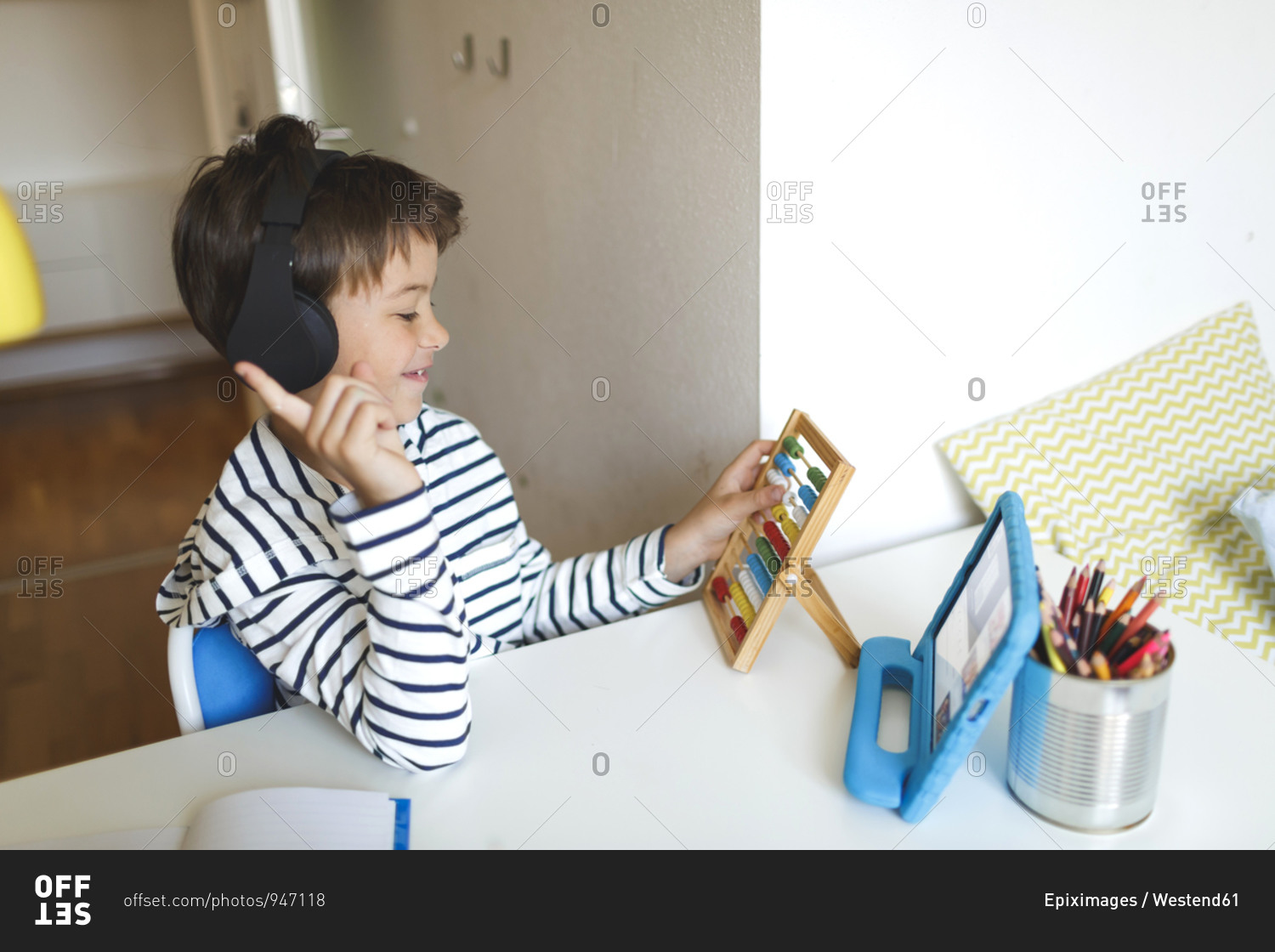 Boy doing homeschooling and using slide rule- tablet and headphones at home