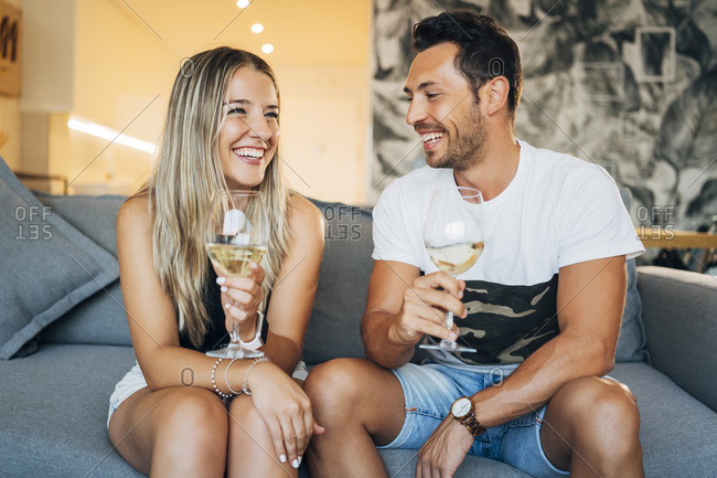 Portrait of happy couple sitting on the couch with glasses of white wine