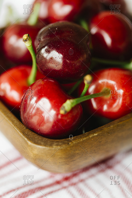 Wood bowl of fresh cherries on a red striped napkin