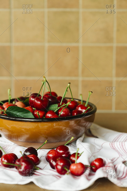Fresh cherries in a ceramic bowl on a red striped napkin
