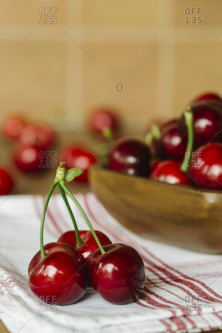 Fresh cherries in a wooden bowl on a red striped napkin
