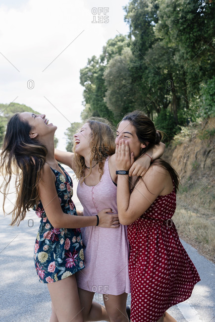 Three happy young happy teenagers hugging on a mountain road