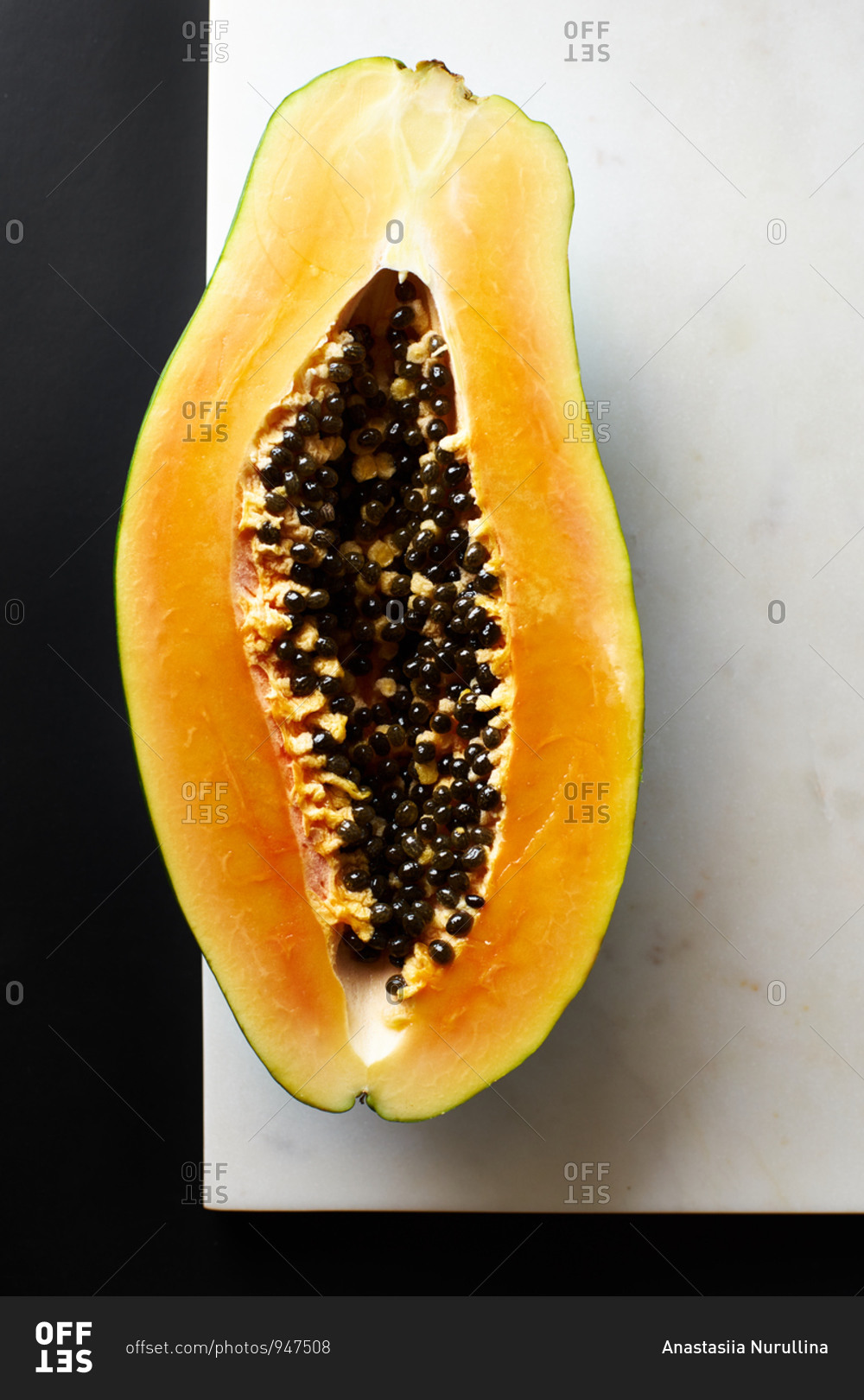 Sliced papaya on marble cutting board on black background
