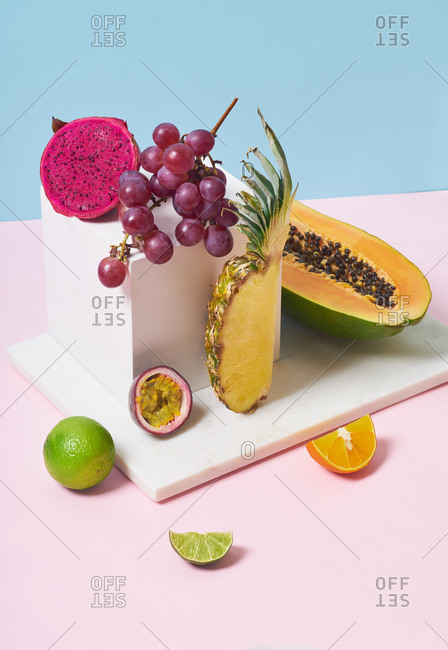 Still life with tropical fruits and white cube on colorful background