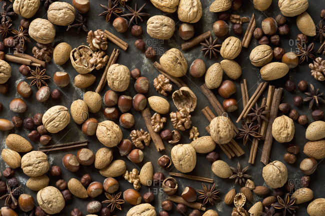 Star anise- cinnamon sticks and various nuts lying on rustic baking sheet