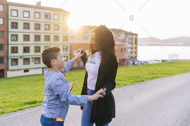 Happy young mother hand in hand with her son at evening twilight