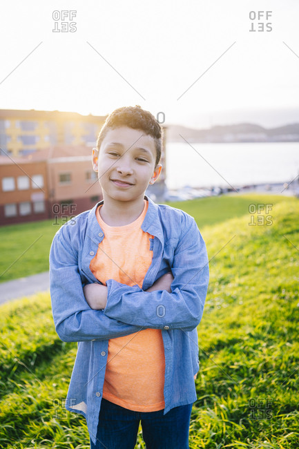Portrait of smiling boy standing on a meadow at evening twilight
