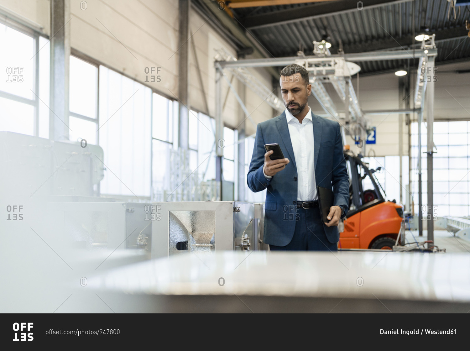 Businessman in a factory checking smartphone