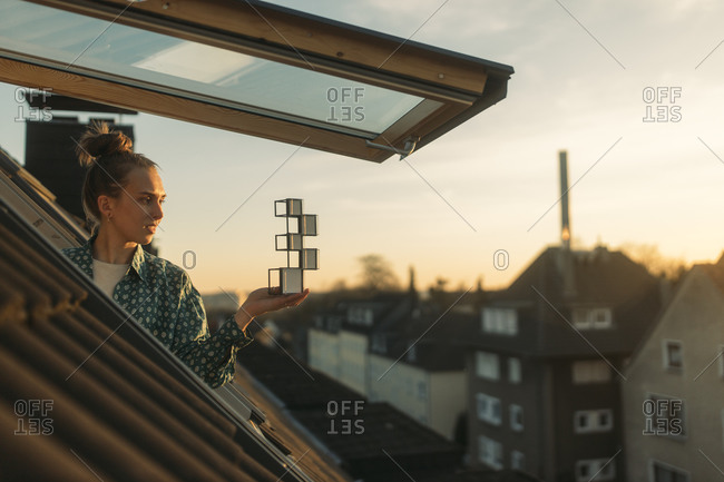 Young woman holding design at the window in the evening