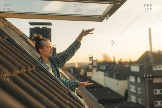 Young woman holding design on string at the window in the evening