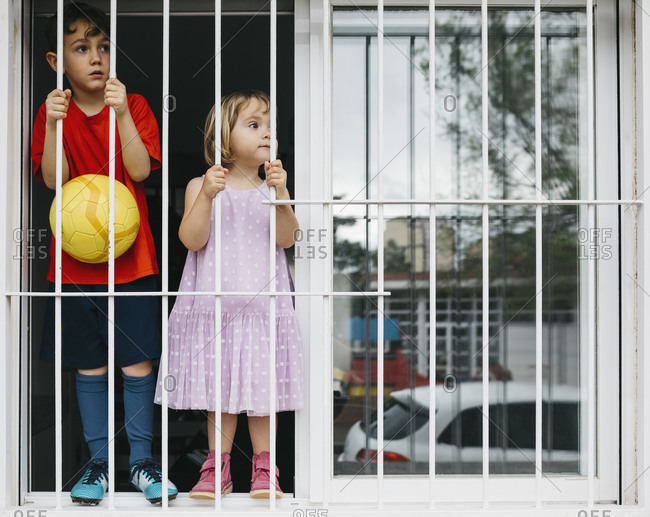 Children standing at open window at window grate