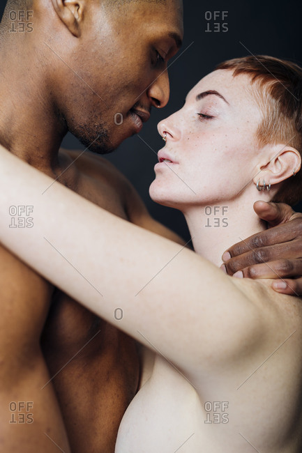 Studio portrait of affectionate nude mixed race couple hugging