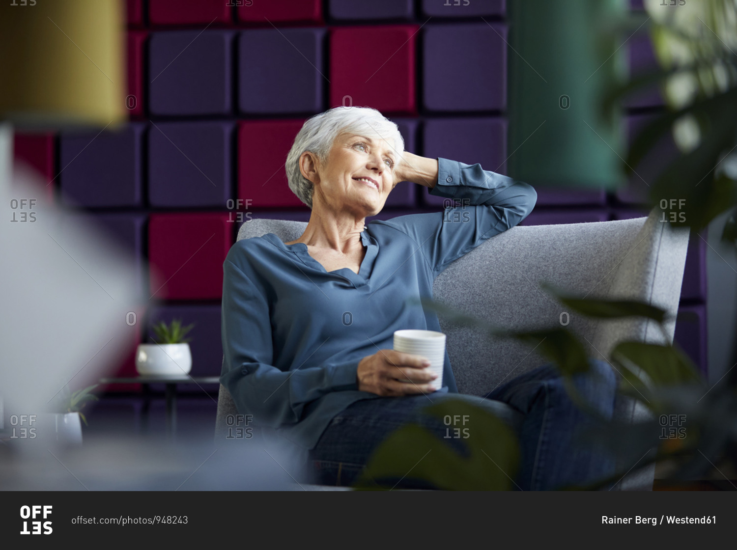 Portrait of smiling senior businesswoman sitting on lounge chair looking at distance